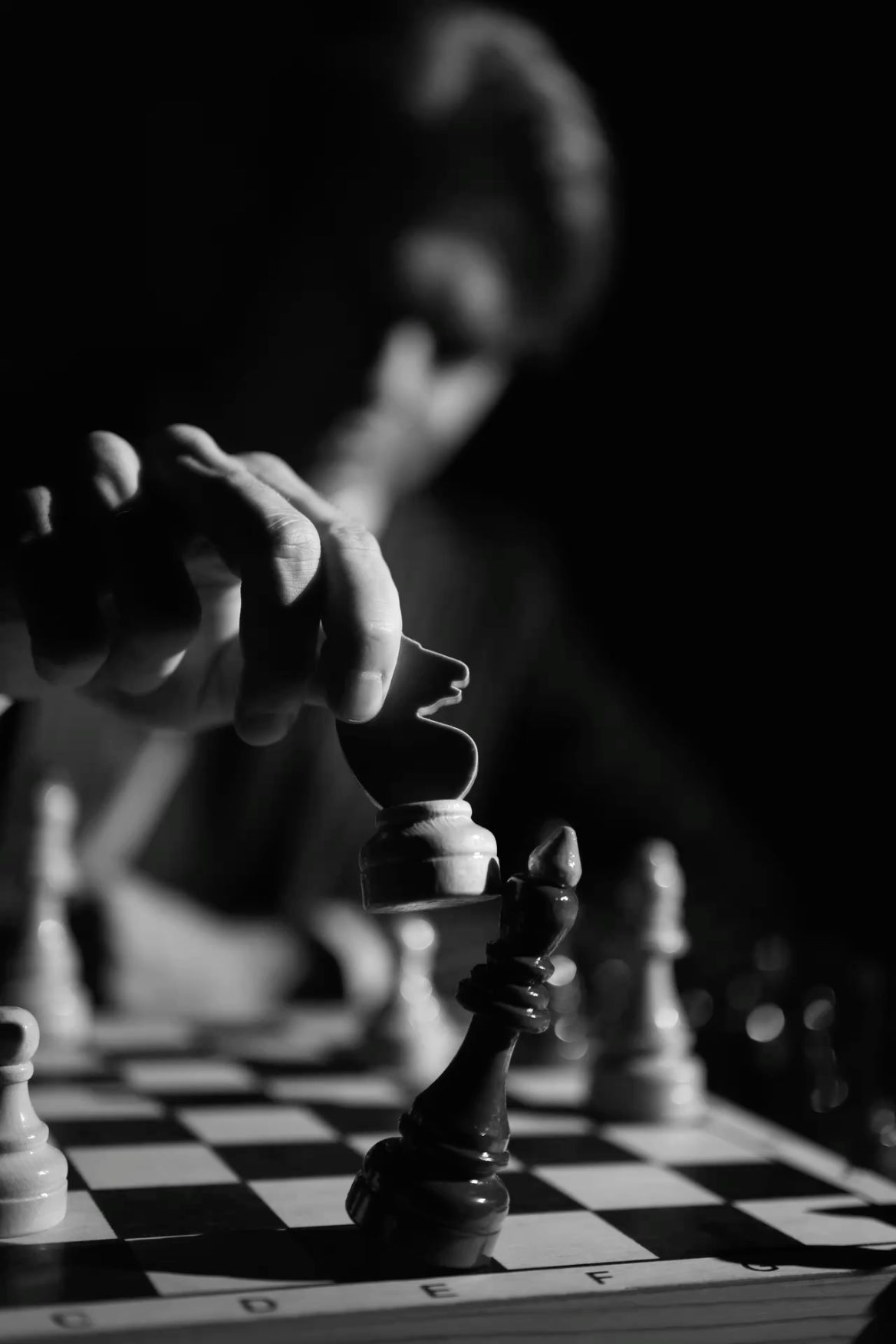 Close-up of a player's hand moving a chess knight in dramatic low light